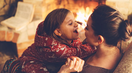 mother and daughter sitting next to fireplace