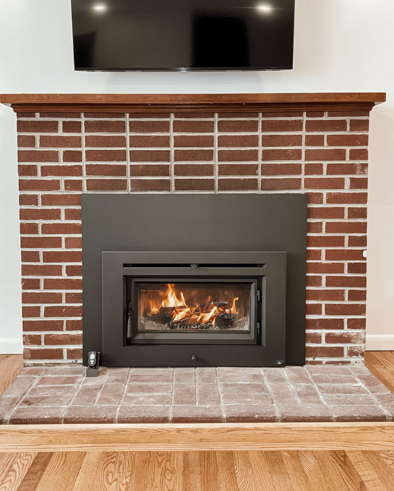 Medium flush wood insert installed in an existing brick fireplace, shown during the first fire after installation in a Norristown, PA home