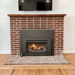 Medium flush wood insert installed in an existing brick fireplace, shown during the first fire after installation in a Norristown, PA home